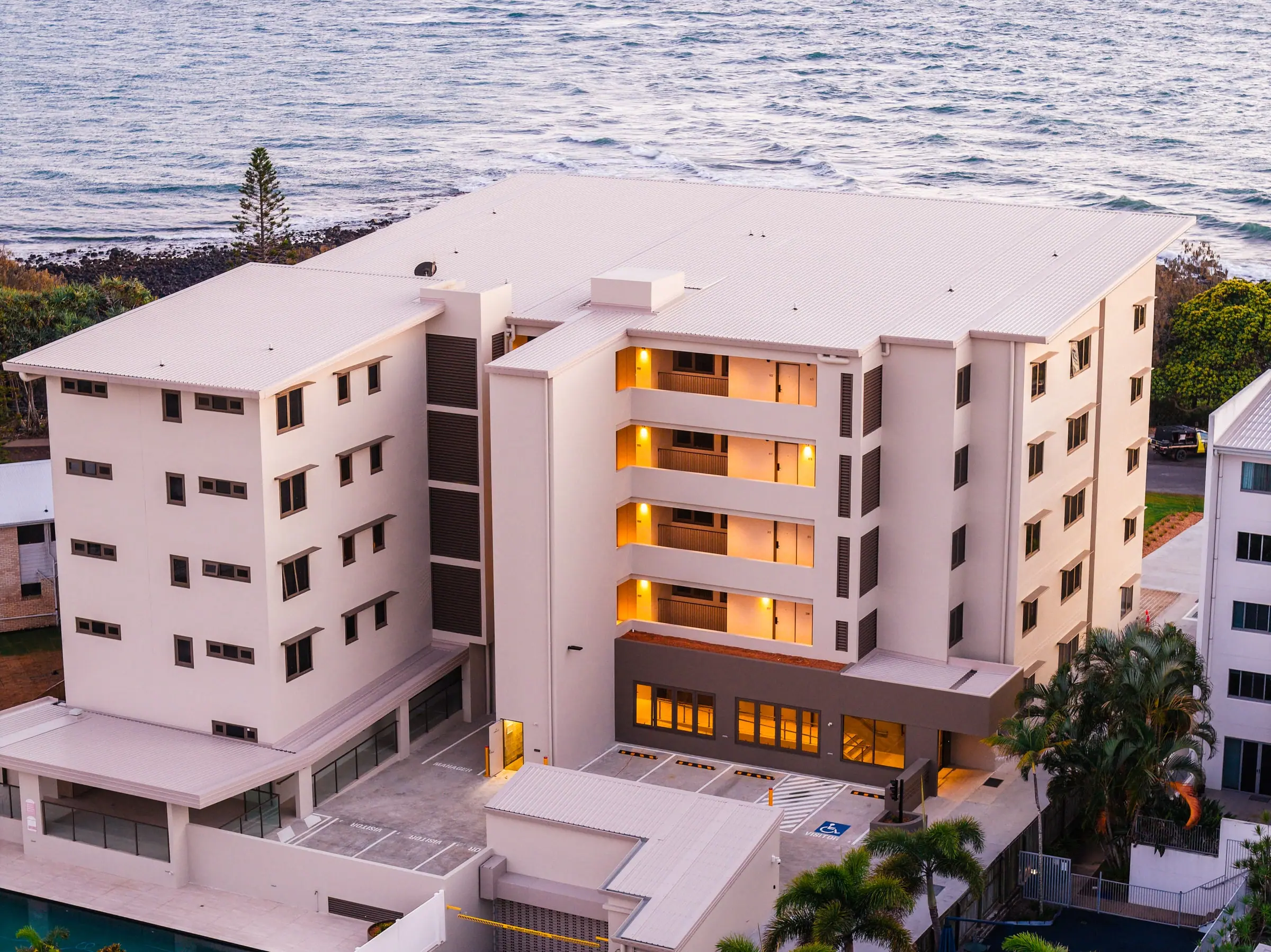 Mira Living at dusk from the air, its lights on above the Esplanade