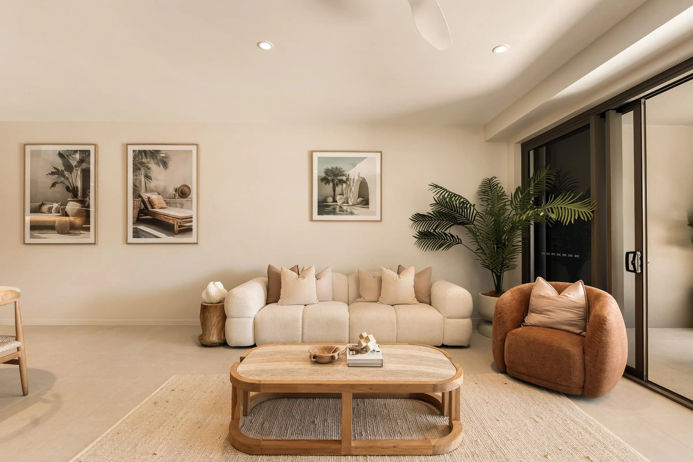 Living room with a curved sofa, artwork and doors to the balcony