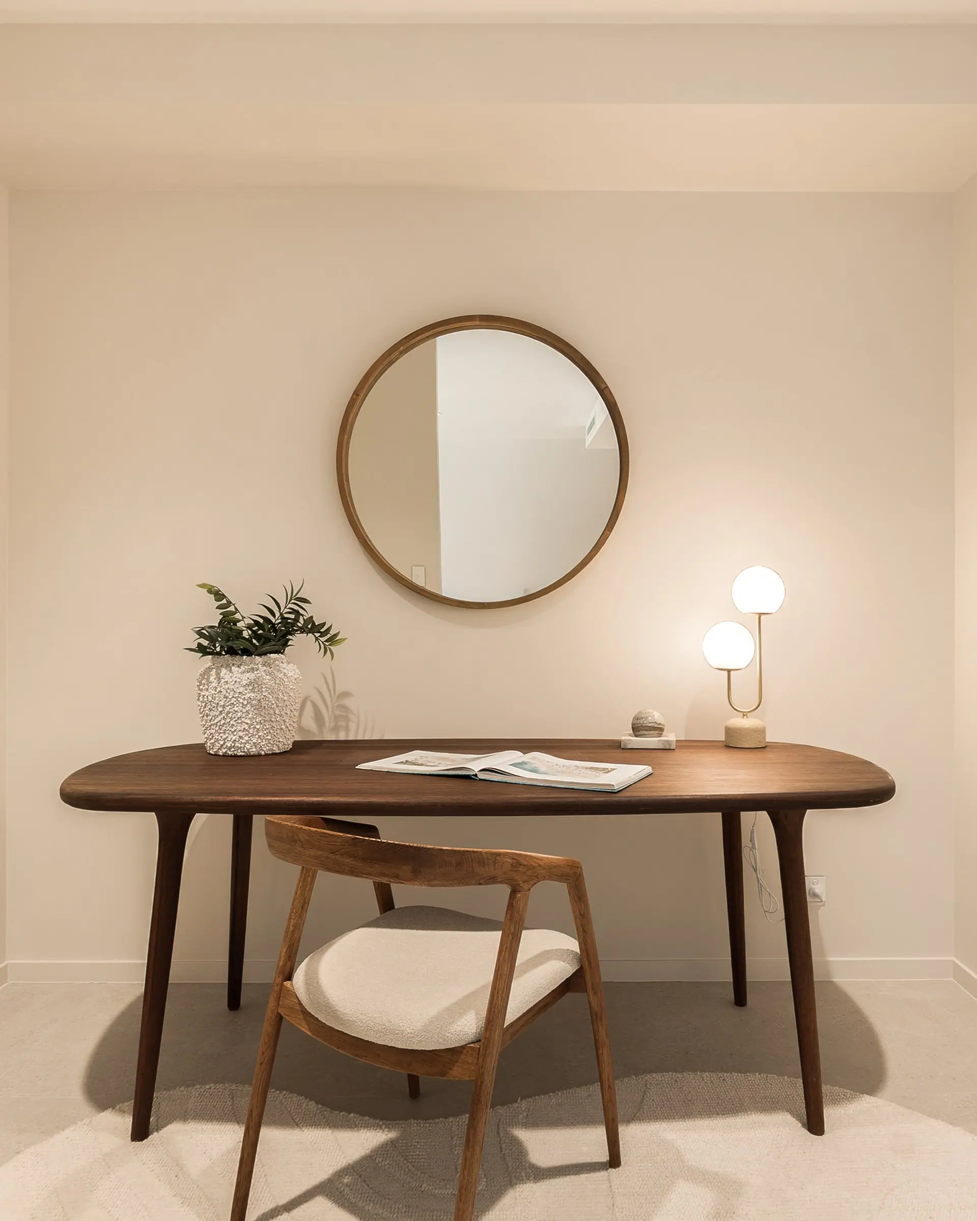 Study nook with a walnut desk and round mirror
